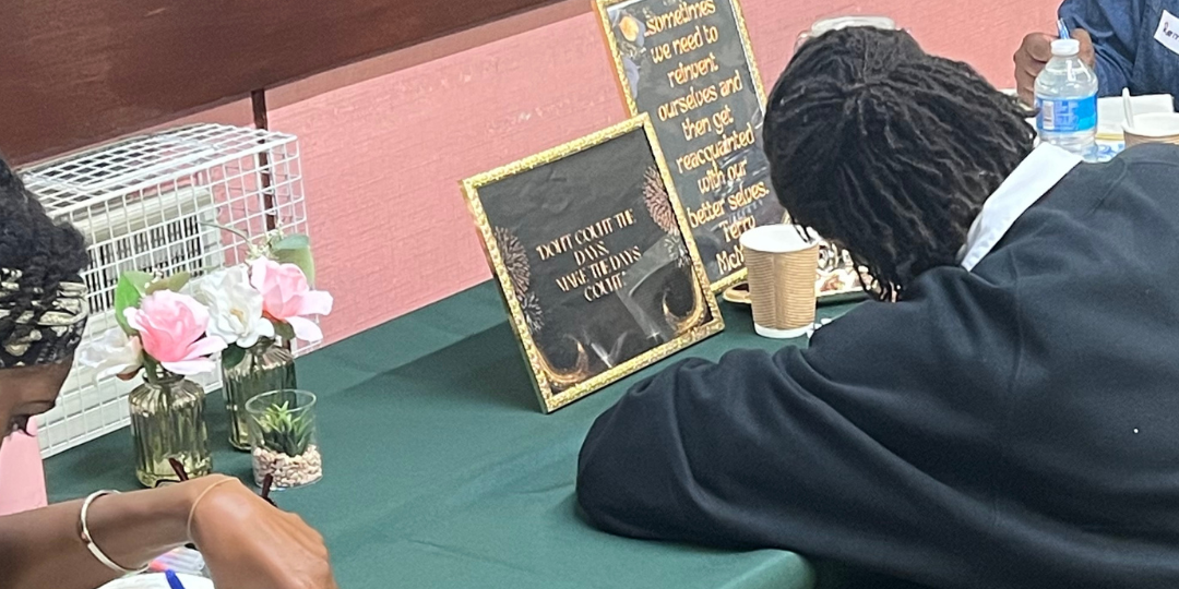 Two black women sit journaling at our wellbeing session